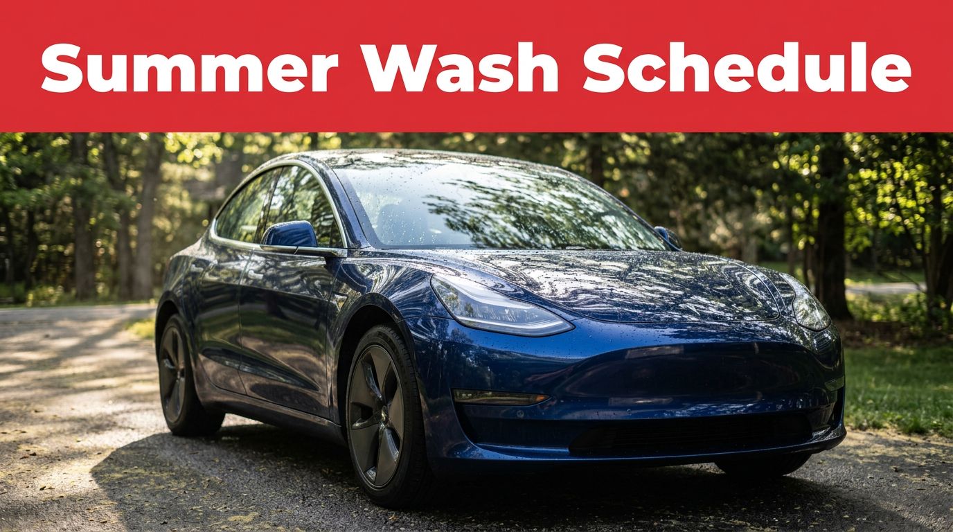 A spotless dark blue car parked in a shaded driveway with water droplets.