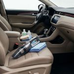 Cleaning supplies, a vacuum, and cloths arranged inside a spotless modern car cabin.
