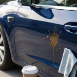 A fresh coffee spill and a microfiber cloth on a glossy dark blue car door.
