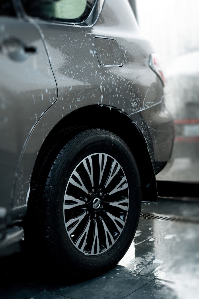 Detailed view of a car wheel during a wash, highlighting shiny rims and water droplets.