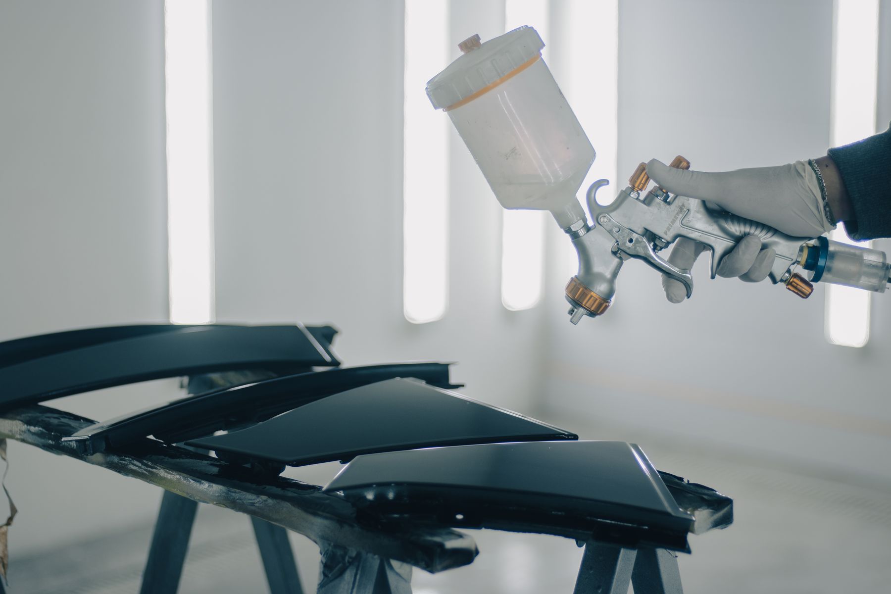 Close-up of car parts being spray painted in a workshop
