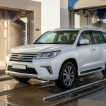 White SUV passing through a car wash at a modern UAE service station.