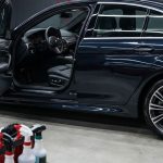 A polished dark sedan sits in a detailing bay beside towels and brushes.