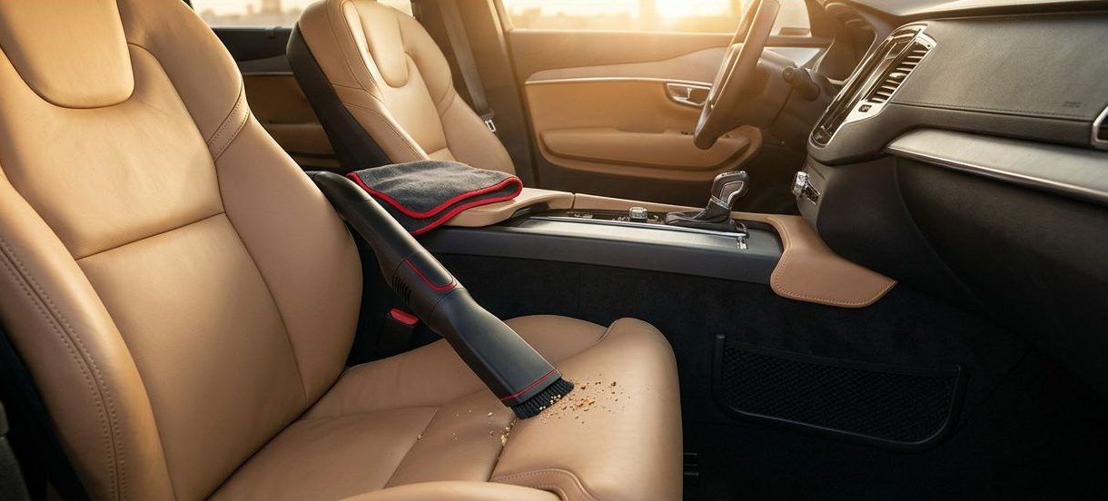 A clean car interior with a vacuum nozzle, leather seats, and a red Fresh Cabin banner.