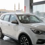 A white SUV is washed at an Ajman car-care station beneath a red headline banner.