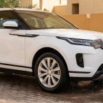 A technician washes a white SUV in a shaded Dubai villa driveway.