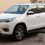 White SUV with a hose and bucket on a Dubai villa driveway.