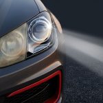 A car shows one cloudy headlight and one clear headlight lighting a dark road.