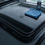 Car sunroof with a microfiber cloth, glass cleaner, rubber seal, and drainage edge.