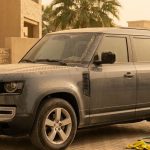 A dusty SUV with a hose and microfiber cloth in a Dubai driveway.