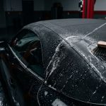 A brush and water gently clean a black convertible roof.