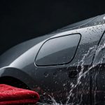 A red cloth and water droplets sit beside a gently rinsed electric car.